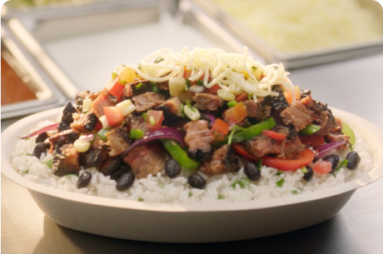 A Smoked Brisket Burrito Bowl with White Rice, Black Beans, Fajita Veggies, fresh hand-chopped Smoked Brisket, Fresh Tomato Salsa, Roasted Chili Corn Salsa, and Monterey Jack shredded cheese.